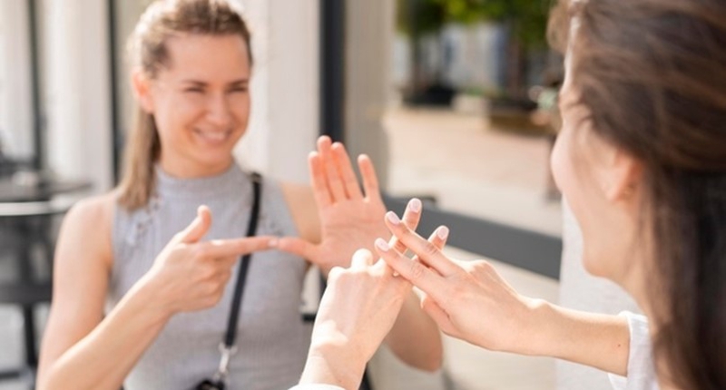 Zdjęcie przedstawia osobę rozmawiającą w języku migowym