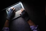 Przed laptopem siedzi haker w rękawiczkach