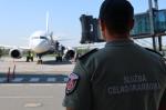 Funkcjonariusz Służby Celno-Skarbowej obserwuje samolot na lotnisku