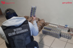 funkcjonariusz Służby Celno-Skarbowej trzyma w ręce nielegalne wyroby akcyzowe, nielegalne papierosy i tytoń w workach