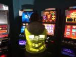 Zdjęcie: funkcjonariusz Służby Celno-Skarbowej, w tle nielegalne automaty do gier hazardowych